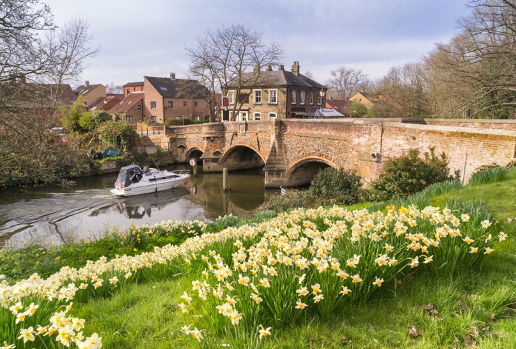 A boat travelling along the river past Bishopgate in Norwich
