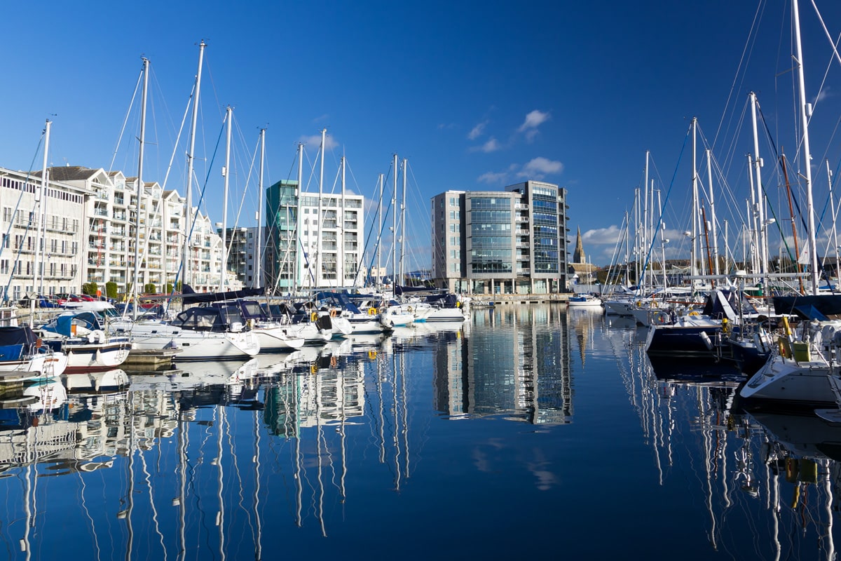 The marina in Plymouth with yachts along the waterfront and skyrise buildings behind