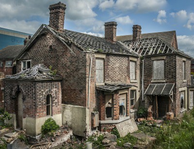 Abandoned and boarded up old house with missing roof tiles. Abandoned and boarded up old house with missing roof tiles.