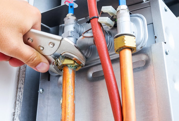 Close up of a plumbers hand repairing a gas boiler.